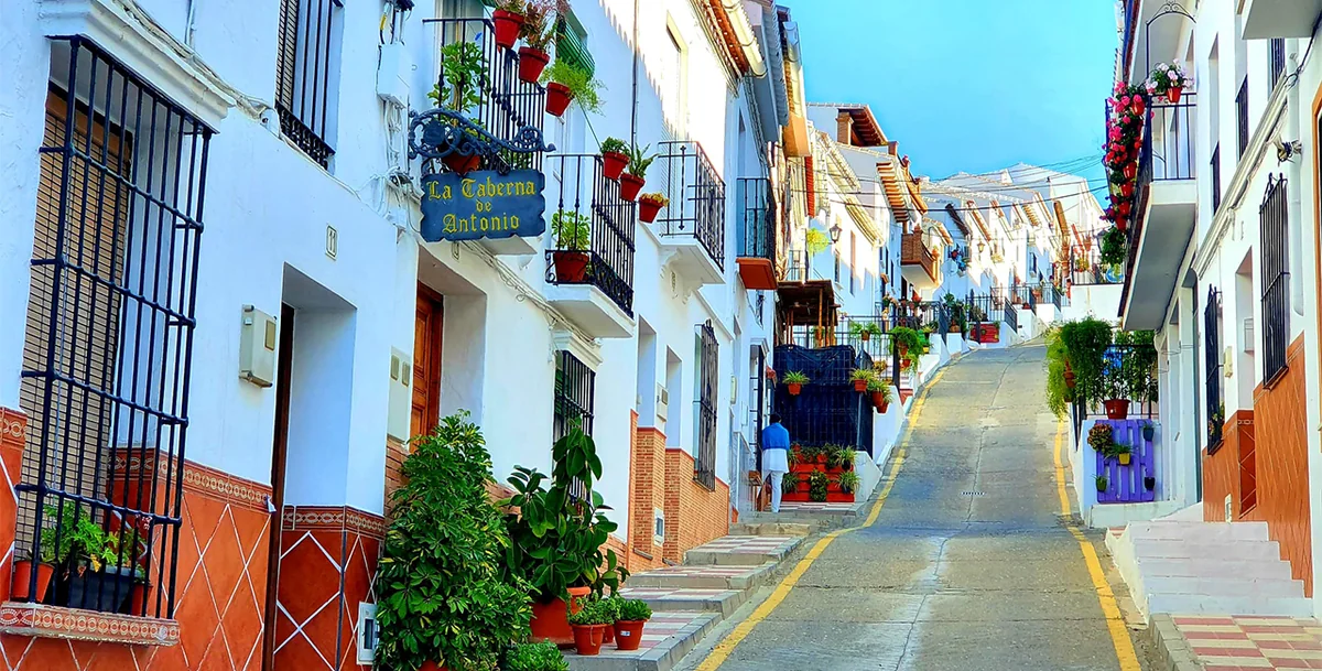 Calle en pendiente de Álora con casas blancas y balcones
